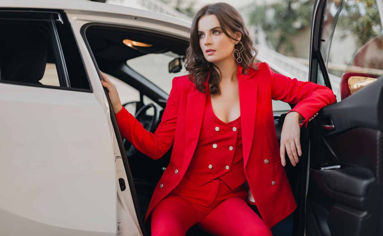 beautiful sexy rich business woman in red suit posing in white car