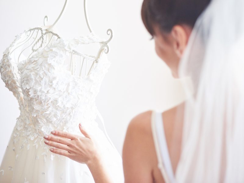 Elegant bride puts a wedding gown in her room.